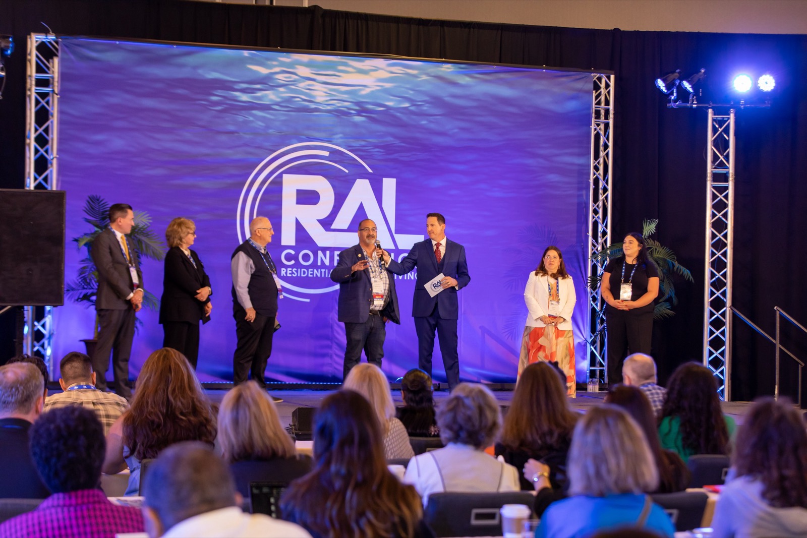 A multi-speaker panel on stage at a Los Angeles conference — audio and coordination both get harder with more people on stage