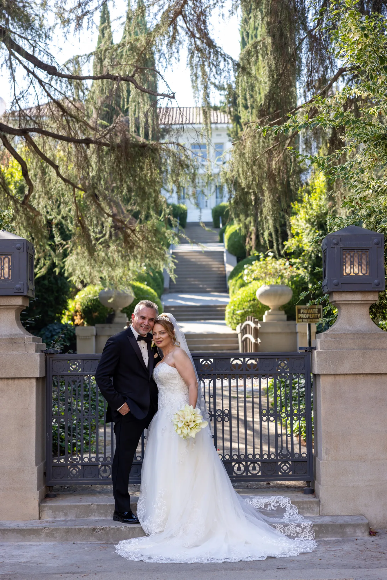 Couple framed by the wrought-iron gates and topiary at Ambassador Mansion & Gardens, Pasadena