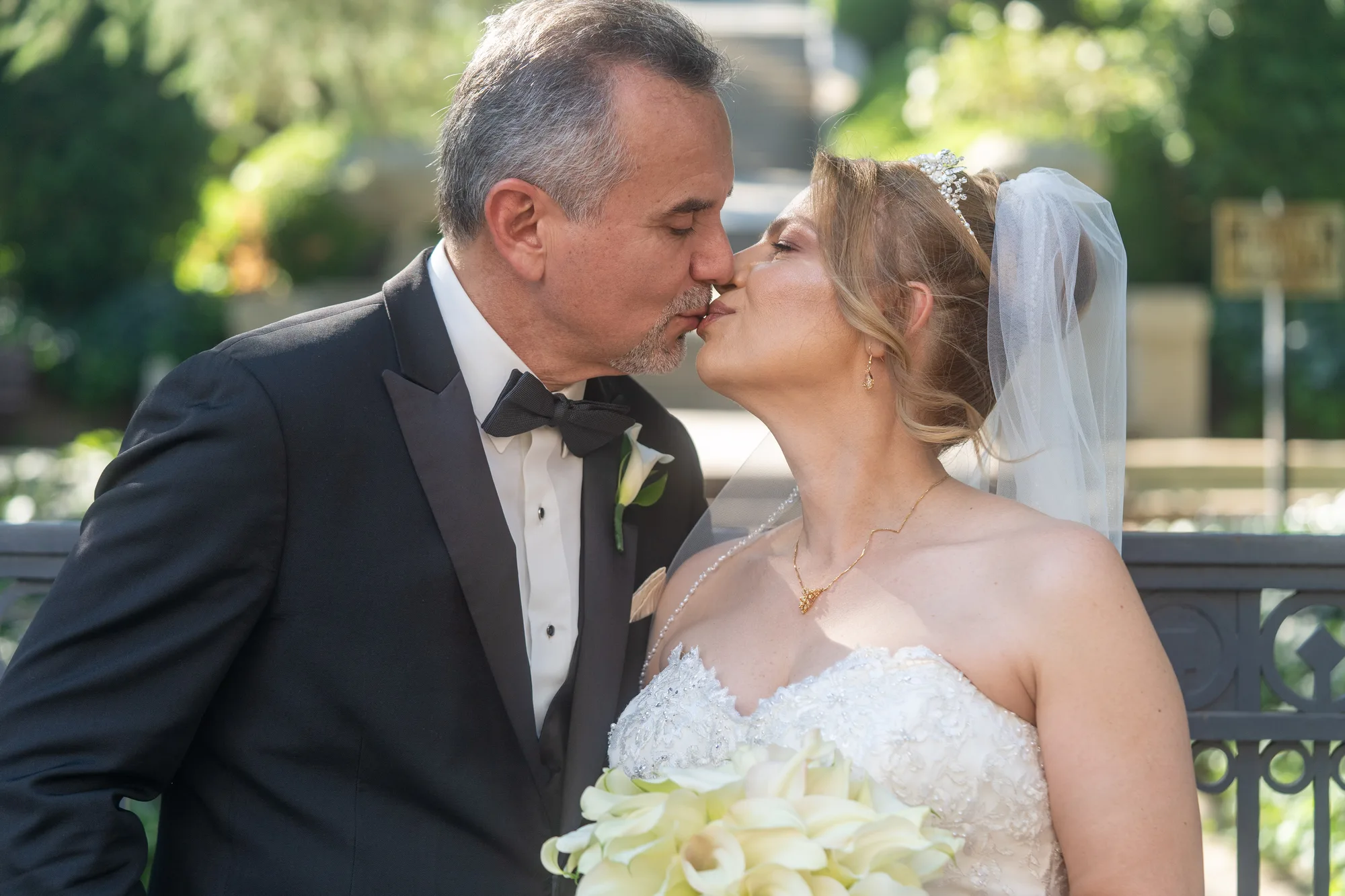 Bride and groom kissing among the garden planting at Ambassador Mansion & Gardens