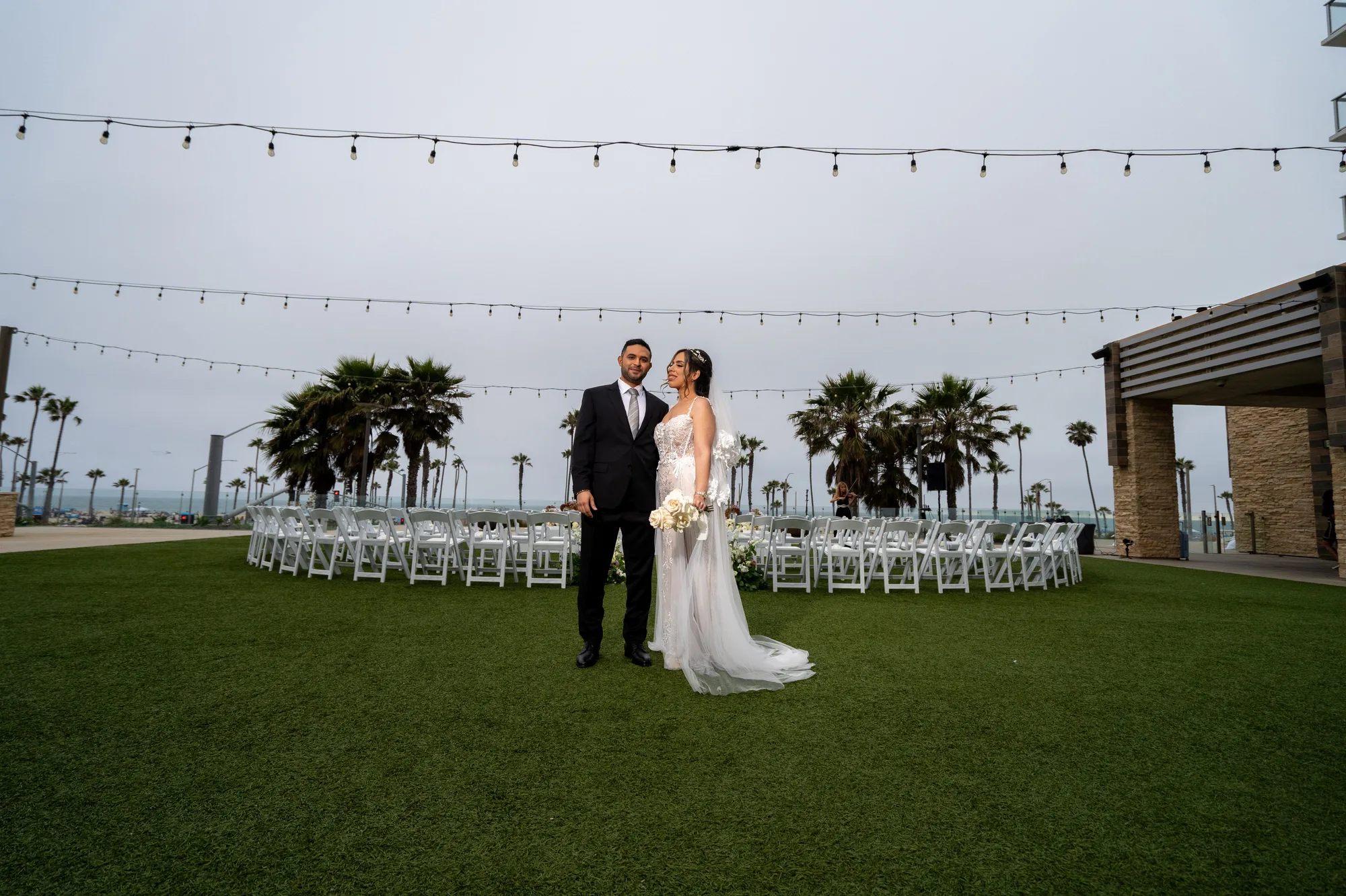 Ceremony set on the Ocean Lawn at Paséa with white chairs and string lights above